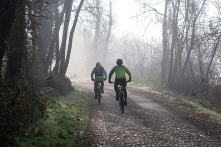 Lonate Pozzolo, Varese - Italy - December 13.2020 Cyclists ride trails in the woods in winter.のeditorial素材