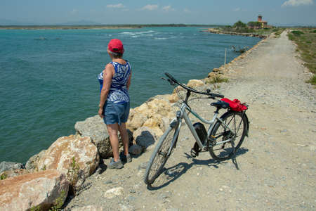 Albarese,Grosseto,Italia - July 29,2021 - Woman with bicycle looking at the seaのeditorial素材