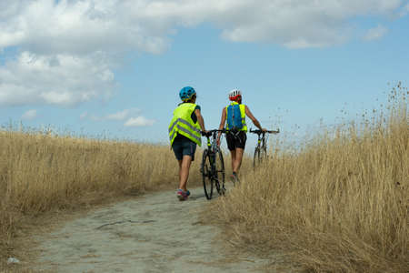 Pienza, Siena-Italy-August 27,2021 Cyclists walking with hand bicycles on the trail