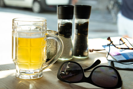 Mug of beer and sunglasses on the table in the restaurantの写真素材