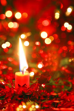 Red Christmas candle with bright bokeh in the background.  Shallow depth of field.の写真素材