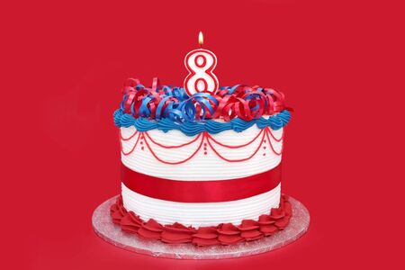 Cake with numeral eight candle.  Vibrant red background.の写真素材