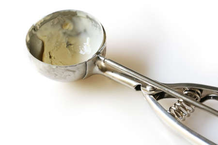 Silver ice cream scoop on white, with remnants of vanilla ice cream.の写真素材