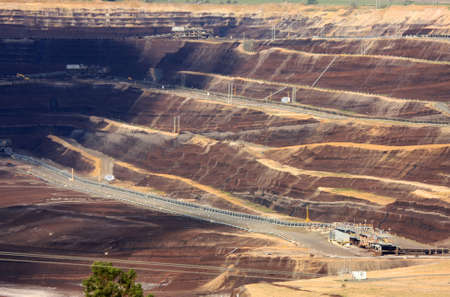 Open-cut brown coal mine, in dappled sunlight.