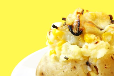 Baked jacket potato stuffed with corn, caramellized onion, cheese and sour cream.  Delicious!の写真素材