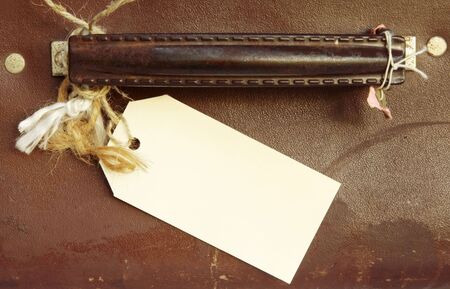 Blank luggage label tied to handle of vintage leather suitcase.  Destination unknown!の写真素材