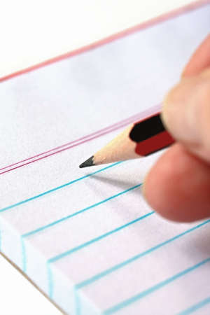 Note taking with pencil over lined white notepad.