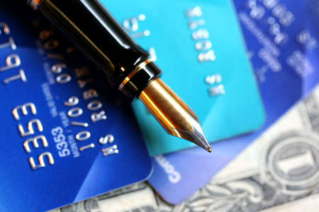 A classic gold-nibbed fountain pen on credit cards and a US $1 bill.  Focus on nib of pen.の写真素材
