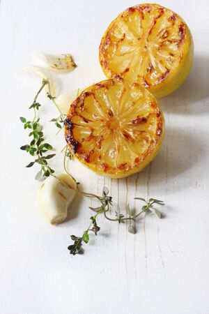 Roasted lemon, garlic and thyme on weathered white timber.  Perfect taste combination of flavours.の写真素材