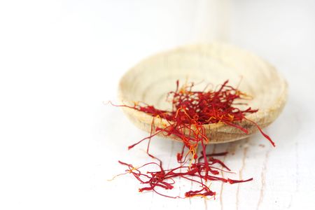 Saffron threads on a wooden spoon, on weathered white timber.の写真素材