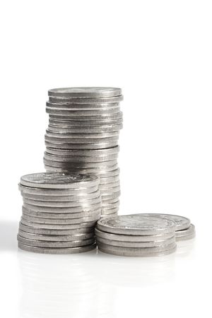 Stacks of silver coins, casting shadow on white.