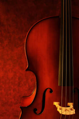 Cello, against canvas background.  Luscious warm tones enhance the beauty of this instrument.の写真素材