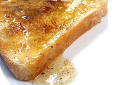 Hot toast dripping with golden honey.の写真素材