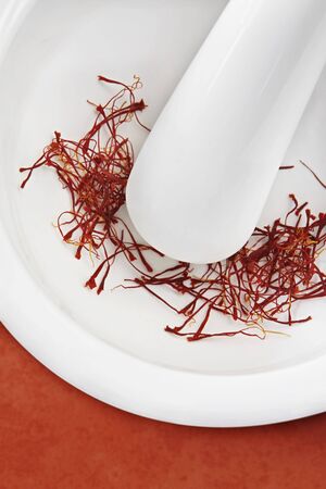 Saffron threads in a white mortar with pestle.  Close-up view of this beautiful spice.の写真素材