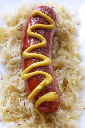 Bratwurst sausage on sauerkraut, with caraway seeds and mustard.の写真素材