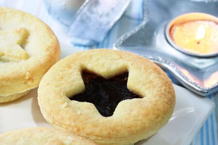 Christmas mince pies with festive blue and silver background, and candle.の写真素材