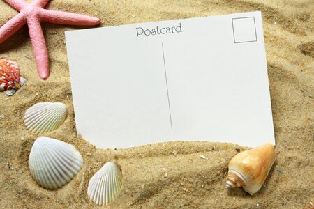 Blank postcard in beach sand, with seashells and a starfish.  Vacation time!の写真素材