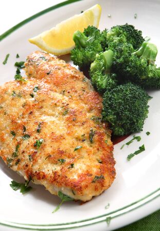 Breaded and herbed chicken fillet, served with broccoli and lemon. Delicious chicken schnitzel.の写真素材