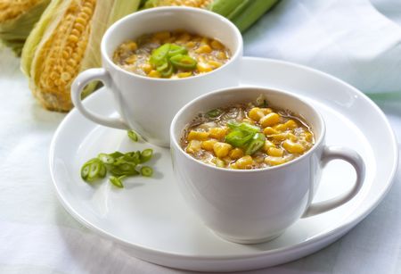 Corn chowder in white cups, with corn cobs behind.  Delicious!の写真素材