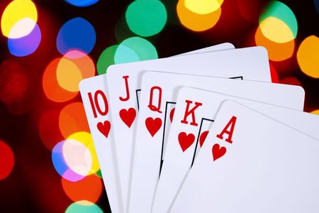 Playing cards showing a royal flush, over background of colorful defocused lights.