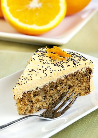 Slice of orange cake with poppyseeds, wth a delicious cream frosting.の写真素材
