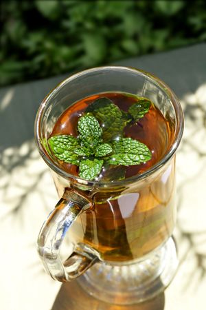 Glass of peppermint tea with fresh mint leaves, sparkling in sunlight.の写真素材