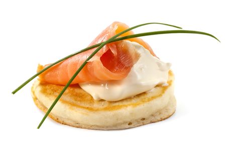 Blini with smoked salmon and sour cream, garnished with chives.  Close-up view, isolated on white.の写真素材