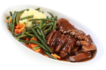 Serving platter of sliced roast beef and gravy, with vegetables.  Isolated on white.の写真素材