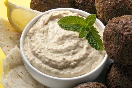 Delicious chick-pea hummus with falafel balls and pita bread.  Garnished with mint and lemon.の写真素材