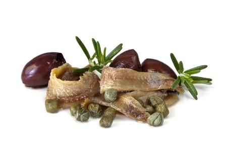 Anchovy fillets with baby capers, pitted black olives, and rosemary, isolated on white.の写真素材