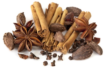 Assortment of spices, over white background.  Includes star anise, cinnamon sticks, black cardamom pods, black peppercorns, and cloves.の写真素材