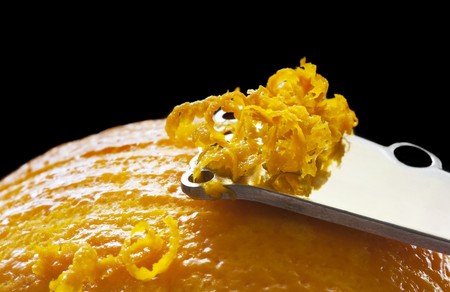 Zesting an orange.  Close-up of zester, with black background.の写真素材