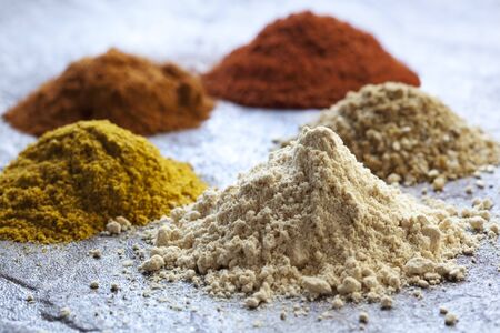 Heaps of different spices; with focus on ginger in front.