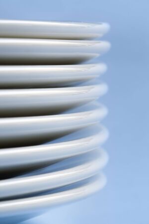Stack of white plates, over pastel blue background.  Soft focus.の写真素材