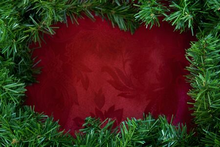 Christmas garland border over rich red brocade fabric.  Lots of copy-space.の写真素材