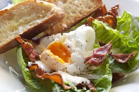 Delicious caesar salad, with baby kos lettuce leaves, bacon bits, toasted baguette, a poached egg, shaved parmesan, and a creamy dressing.の写真素材