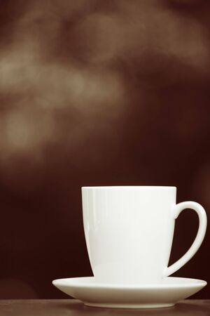 White coffee mug and saucer, over sepia toned background.  Lots of copy-space.の写真素材