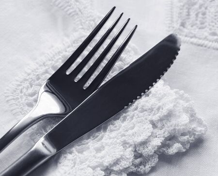 Knife and fork on lace napkin and tablecloth.  の写真素材