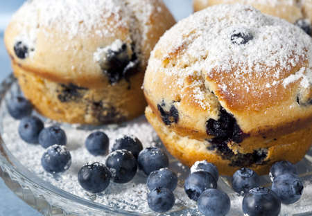 Fresh blueberry muffins, dusted with icing sugar, on crystal plate.の写真素材