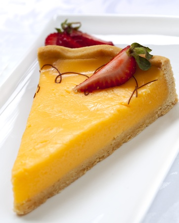 Slice of lemon tart, garnished with strawberry.の写真素材
