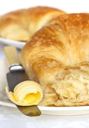 Butter curl on knife, with fresh croissants.の写真素材