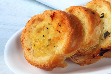 Garlic bread with herbs, on white serving dish.