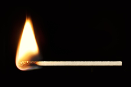 Horizontal burning match isolated on black background の写真素材