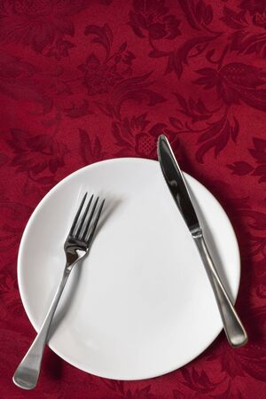 Place setting on red brocade tablecloth.  Overhead view.の写真素材