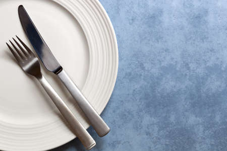 Cutlery on white plate over blue background   Lots of copy-space の写真素材