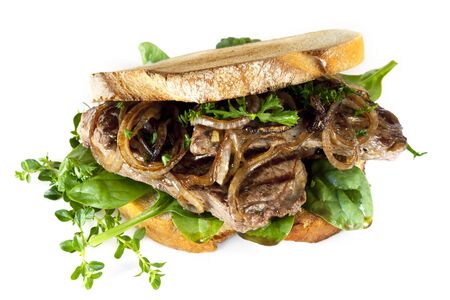 Steak sandwich made with sourdough bread, caramelized onions and fresh herbs, isolated on white の写真素材