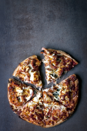 Gourmet pizza over stone.  Topped with smoked salmon, spinach, capers, tomatoes, cream cheese.の写真素材