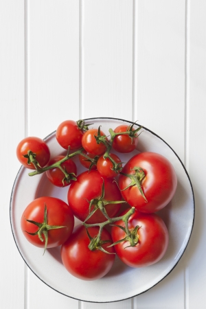Vine tomatoes in rustic enamel bowl over white timber   Lots of copy space の写真素材