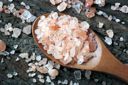 Spoonful of pink Himalayan rock salt, over weathered timber.