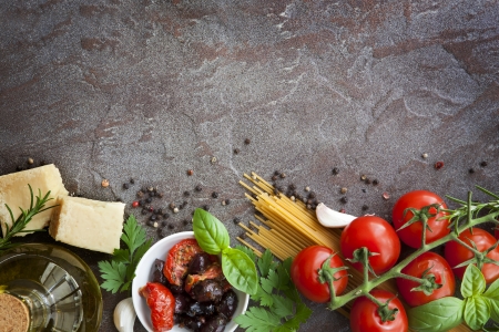 Italian food background, with vine tomatoes, basil, spaghetti, mushrooms, olives, parmesan, olive oil, garlic, peppercorns, rosemary, parsley and thyme   Slate background の写真素材